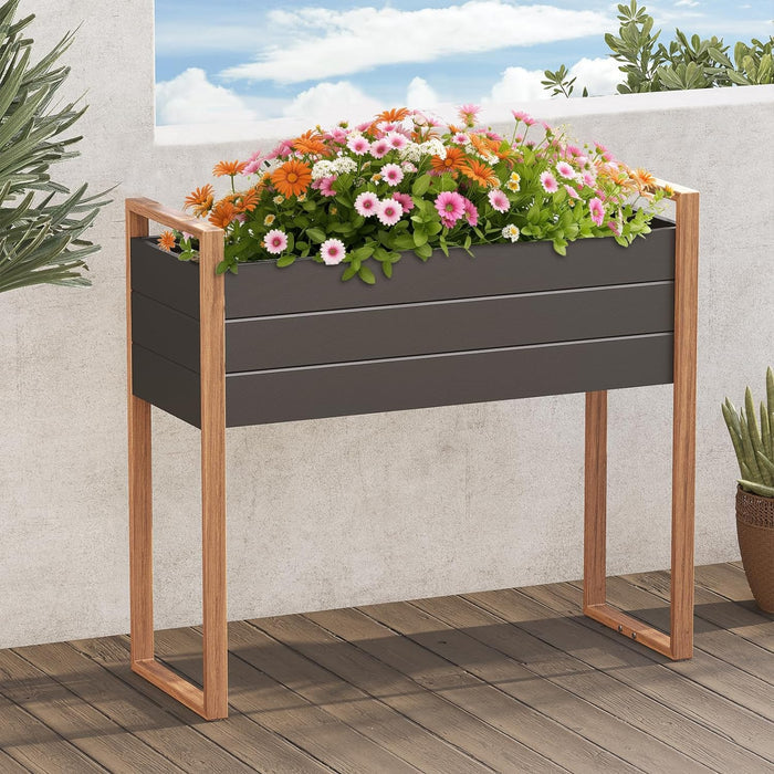 Gray planter box with wooden frame filled with flowers on a wooden deck.