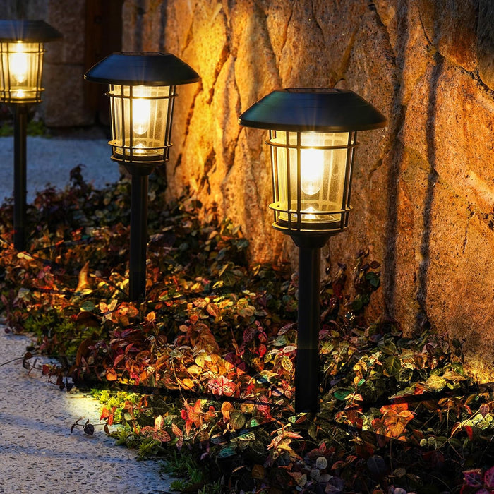 Three garden lights illuminating a stone wall and pathway