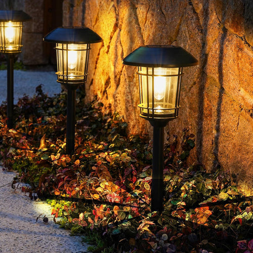 Three garden lights illuminating a stone wall and pathway