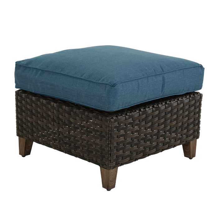 Wicker ottoman with a blue cushion on a white background