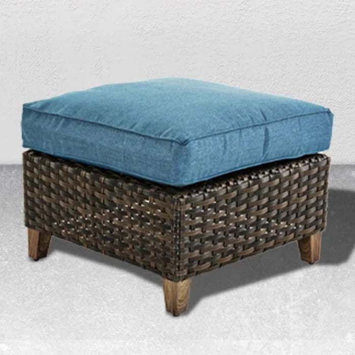 Wicker ottoman with a blue cushion on a light gray background