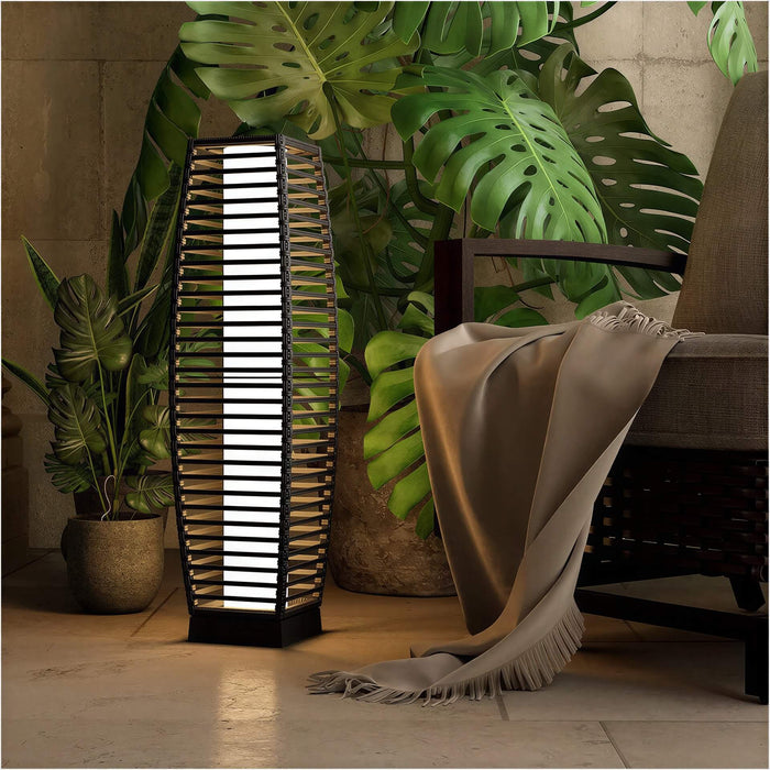 Grand Patio outdoor solar-powered crossover woven resin wicker floor lamp beside a chair and plants in a cozy setting.