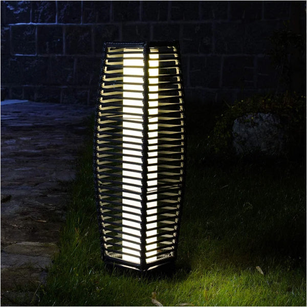 Grand Patio outdoor solar-powered crossover woven resin wicker floor lamp with a tall, textured design illuminated at night.