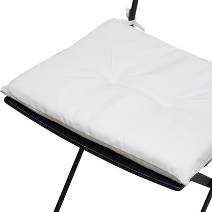 White pillow on a black chair with a white background